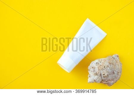Unmarked White Tube With Moisturizer And A Cockleshell On A Yellow Background. Concept Of Skin Care