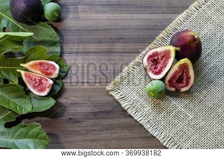 Figs, green leaves on rustic wooden background
