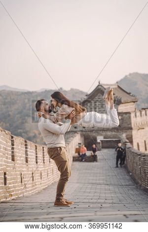 Beautiful Young Couple Running And Jumping At The Great Wall Of China.