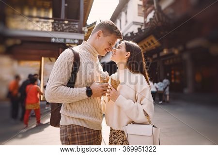 Newlywed Couple Eating Ice Cream From A Cone On A Street In Shanghai Near Yuyuan China.