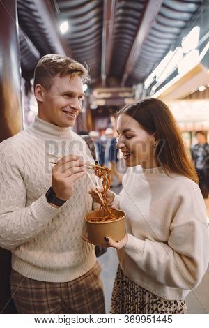 Newlywed Couple Eating Noodles With Chopsticks In Shanghai Outside A Food Market