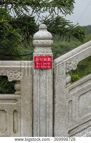 Small Red Sign On A Concrete Post With Chinese Writing Translating To 'be Careful, No Playing