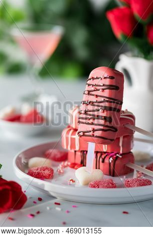 A Decorated Valentine Cakesicle Leaning Against Other Cakesicles On A Plate.