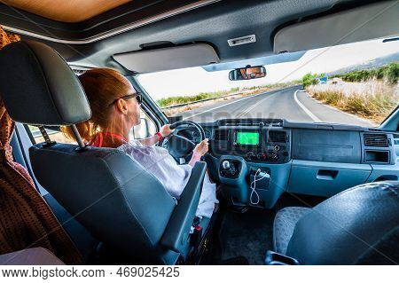 Woman Is Driving Motorhome Or Campervan On The Road Outdoors In Nature.