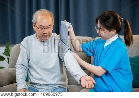 Asian Nurse Visit Patient Senior Man At Home She Measuring Arterial Blood Pressure On Arm In Living 