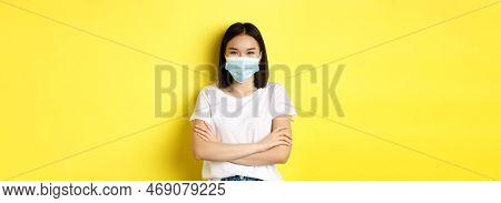 Covid, Health Care And Pandemic Concept. Asian Woman In White T-shirt And Medical Mask Cross Arms On