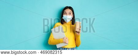 Covid-19, Health Care And Quarantine Concept. Asian Girl Student In Medical Mask Standing With Lapto