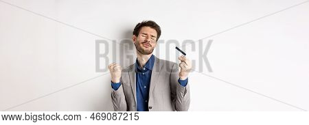 Excited Successful Businessman Dancing With Plastic Credit Card, Raising Fist Pumps And Smiling Deli