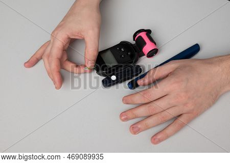 A Man With Diabetes Puts A Test Strip Into The Meter To Find Out His Blood Sugar Level.