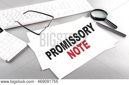 Promissory Note Text On A Paper With Keyboard, Calculator On A Grey Background