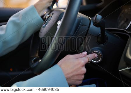 Close-up Woman Finger Pressing The Start Stop Engine Button On Modern Car. Woman Driver Pushing A St