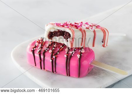 Valentines Day Cakesicles On A Marble Slab With A Bite Out Of The One On Top.