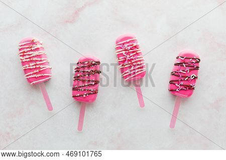 Four Bright Pink Cakesicles For Valentines Day Against A Light Background.