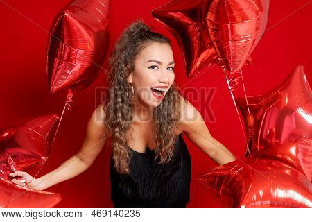 Beautiful Young Joyful Girl Is Holding Bunch Red Star Balloons On Red Background. Shes Holiday Party