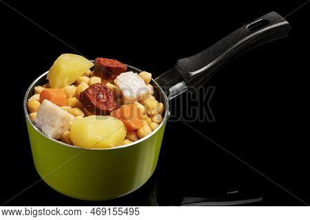 Cooked (cocido, Guiso) Stew, Chickpeas With Chorizo, Bacon, Carrot And Potato In A Green Saucepan An