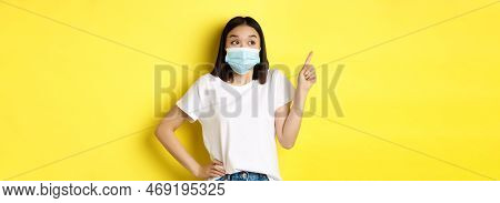 Covid, Health Care And Pandemic Concept. Asian Woman In Medical Mask And White T-shirt Pointing Fing