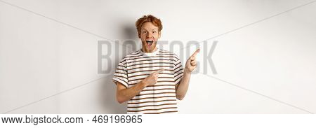 Cheerful Man With Red Hair Checking Out Promo Offfer, Pointing Left At Logo And Smiling At Camera, S