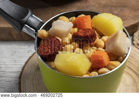 Cooked (cocido, Guiso) Stew, Chickpeas With Chorizo, Bacon, Carrot And Potato In A Green Saucepan An