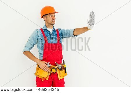 Shows Stop Sign By Hand. Construction Worker In Uniform And Safety Equipment Have Job On Building