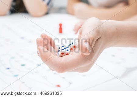Cropped Photo Of Group Of Children Sitting At Table, Playing Tabletop Game, Holding White Dices Over
