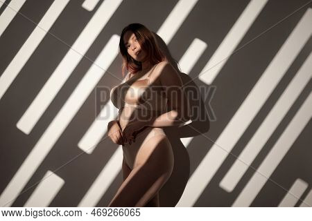 Plump Young Woman In Lingerie Posing In The Light Of A Gobo Mask