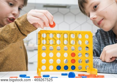 Portrait Of Two Preteen Boys Friends Children Sitting At White Table In Kitchen At Home, Playing Boa