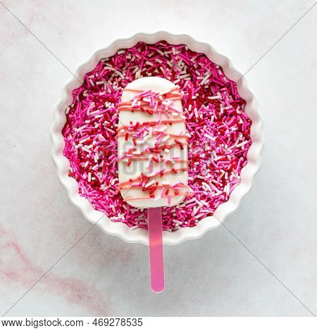 A Homemade Decorated Valentine Cakesicle In A Bowl Of Bright Sprinkles.