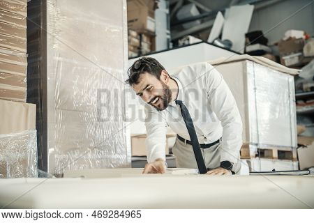 A Smiling Headman Counting Sheets On The Pile At Printing Shop.