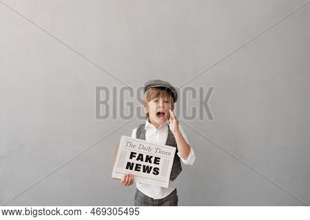 Newsboy Shouting Against Grunge Wall Background. Boy Selling Fake News