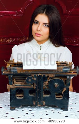 Giovane bella donna digitando una lettera con typewritter antiquariato