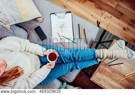 Top View Woman Relaxing, Drinking Tea After Drawing Work-life Balance Wheel Sitting On The Sofa At H