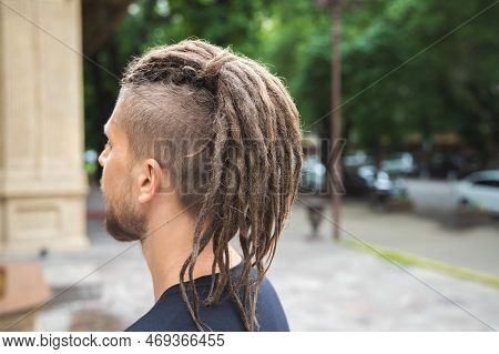 Back View Of A Caucasian Man With Dreadlocks And Sidecut On A Summer Street
