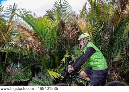 Senior Adult Man Enjoying Bike Ride In Outdoor Tropical Place. Peaceful Retiree Enjoying His Free Ti