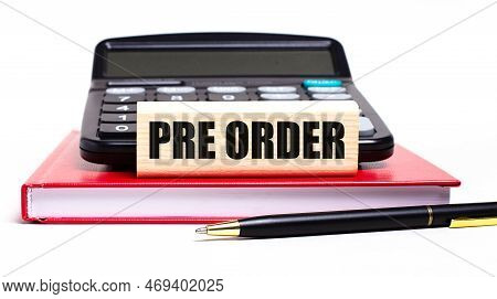 A Burgundy Notebook On A White Background. On It Is A Black Calculator, A Pen And A Wooden Block Wit