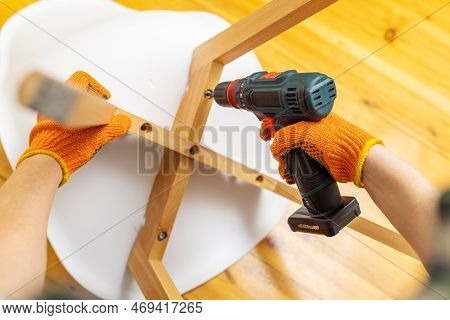 Assemble Furniture. Man Assembling Chair. Furniture Assembler With Drill