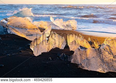 Diamond Beach In Iceland. Icebergs Shining On Black Volcanic Sand. Clear Ice Crashed By Ocean Waves.
