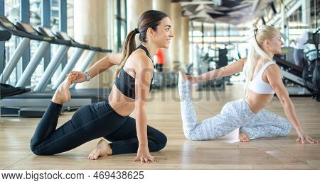 Two Attractive Sporty Women Doing Yoga Exercise During Class At Gym.