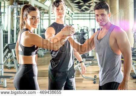 Happy Young Athletic People In Sportswear Giving Hands Greeting To Each Other In Gym.