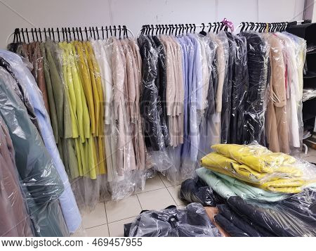 Coat In Stock. Colorful Coats Hang On Metal Racks In The Warehouse And Lie On The Floor. New Clothes