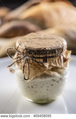 A Jar With Homemade Rye Sourdough, Fresh Bread In The Background.