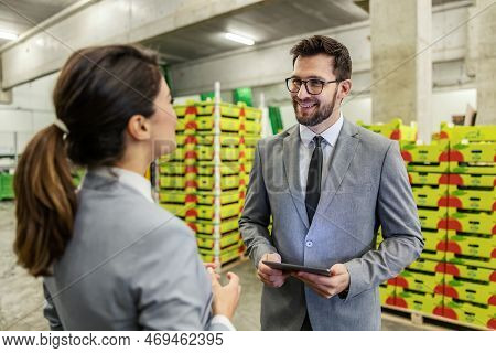 Warehouse Manager Training. A Man And A Woman In A Business Suit Stand In A Warehouse And Talk About