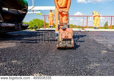 View On Worker Who Is Compacting Asphalt With Vibration Plate, Compactor Machine On The Bridge Under