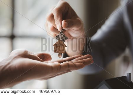 A Home Rental Company Employee Is Handing The House Keys To A Customer Who Has Agreed To Sign A Rent