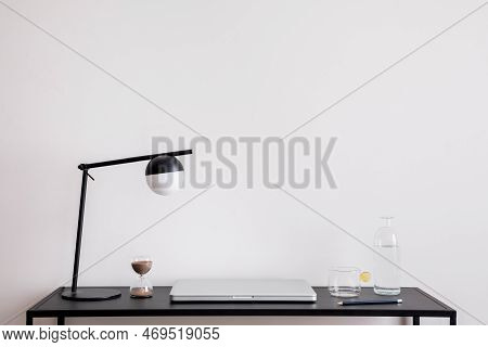 Minimalist Composition Of Office Interior With Copy Space, Black Desk, Laptop, Table Lamp And Person