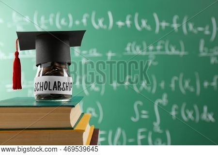 Scholarship Concept. Glass Jar With Coins, Graduation Cap And Books Against Greenboard, Space For Te