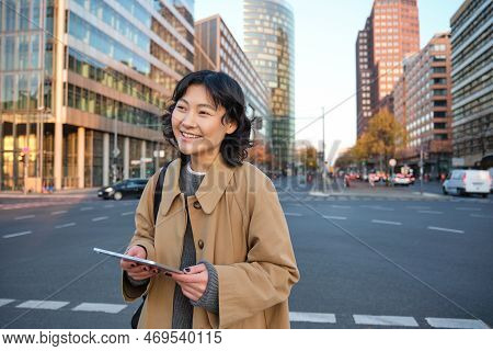 Portrait Of Smiling Korean Girl Stands On Busy Street Of City Centre, Holds Digital Tablet, Casual R