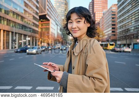 Woman Walking On Street Using Digital Tablet, Holding Gadget In Hands And Looking Away, Standing In 