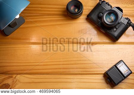 Top View Of Analog Camera, Flash And Lens On Wooden Table, Professional Photography Equipment. Photo