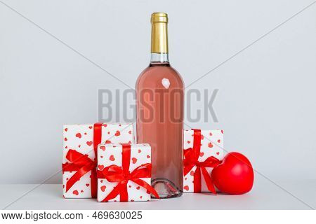 Bottle Of Wine On Colored Background For Valentine Day With Gift Box. Heart Shaped With Presrnt Box 
