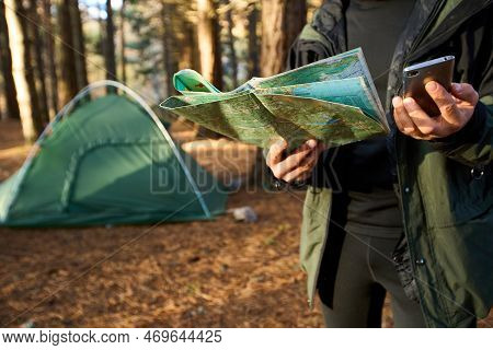 Adult Hiker With Backpack Using Mobile Phone And Map In Forest Near His Tent. Hiking Elderly Man In 